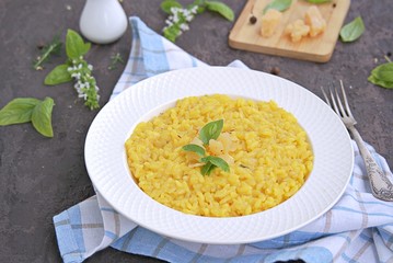 Saffron risotto in a white plate on a dark concrete background.