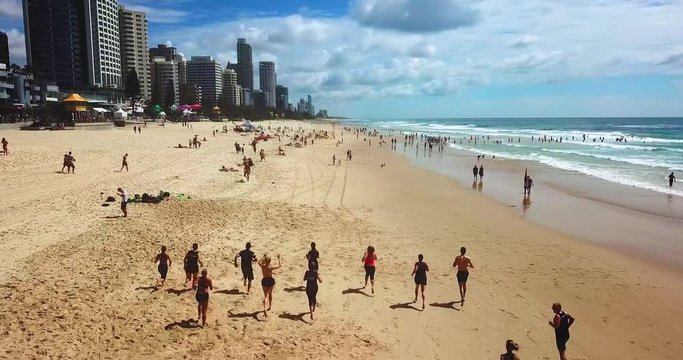 Aerial tracking view of people jogging along the beach. Gold Coast city, Australia.