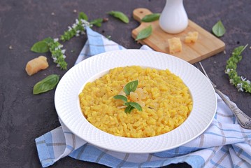Saffron risotto in a white plate on a dark concrete background.