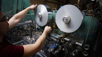 Worker make operationwith roll of paper for cigarettes packing