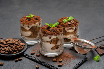 Classic tiramisu dessert in a glass on stone serving board on dark concrete background