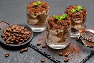 Classic tiramisu dessert in a glass on stone serving board on dark concrete background