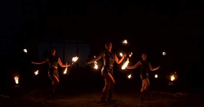 A group of professional artists with fire show the show juggling and dancing with fire in slow motion.