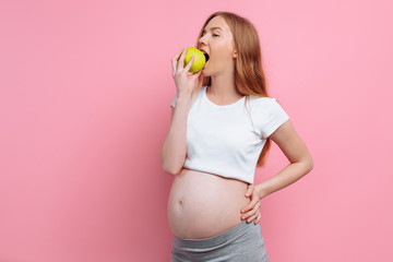 Pregnant woman bites a green apple. The concept of pregnancy, maternity, proper nutrition