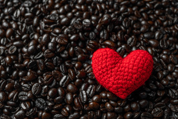 red heart on a lot of roasted coffee beans background. Strong black espresso, Grains of coffee background, texture