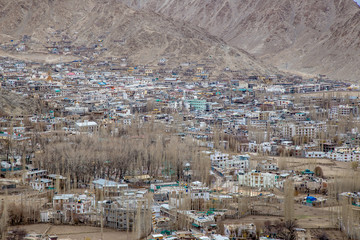 Fototapeta premium Leh Ladakh city view from Shanti Stupa. Beautiful amazing village in the valley with snow mountain at background. Ladakh, India.