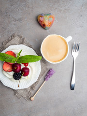 Meringue dessert Pavlova cake with fresh berries on a plate and cup of coffee. Stone background, close-up