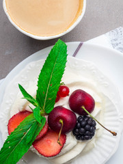 Dessert pavlova meringue with whipped cream and mint leaf decoration and cup of coffee
