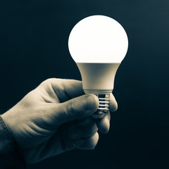 human hand holding the included led lamp on a dark background