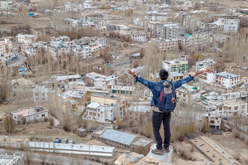 Traveler man standing on Leh Ladakh city view from Shanti Stupa. Beautiful amazing village in the valley with snow mountain at background. Ladakh, India.