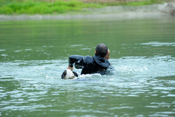 Men in a wet diver suit (lifeguards) showing right way of holding the drowning on the water surface