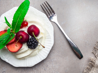 Meringue dessert Pavlova cake with fresh berries on a stone background, sackcloth decoration