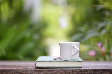 White heart shape cup and notebook at outdoor