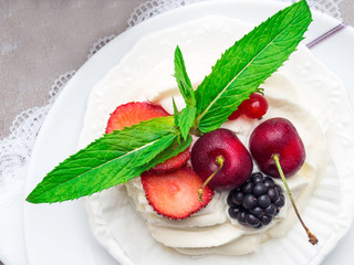 meringues pavlova cake with fresh cherry, blackberry, strawberry on concrete background