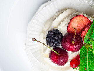 meringues pavlova cake with fresh cherry, blackberry, strawberry on concrete background