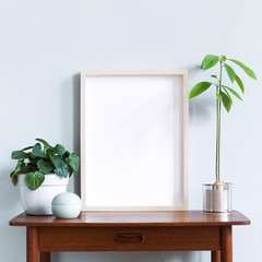 Stylish scandinavian interior with design retro table, white mock up photo frame and beautiful plants in design pots and accessories. Modern home decor. Gray background wall. Minimalistic concept.