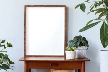 Stylish scandinavian interior with design retro table, brown mock up photo frame and beautiful...
