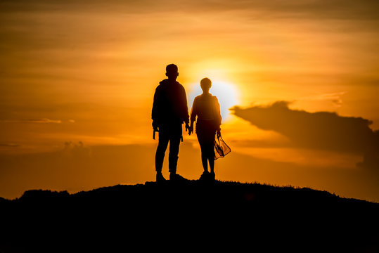 Love young couple Holding hands looking at the sunset