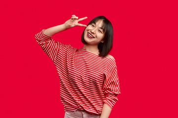 Cheerful Asian woman gesturing V sign