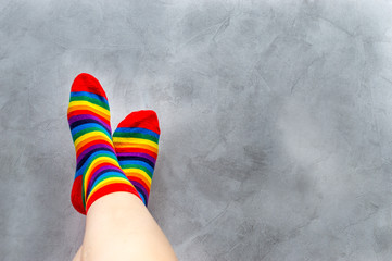 On a gray background, close-up of the feet of a man in multi-colored socks. Rainbow. Symbol. Concept LGBT