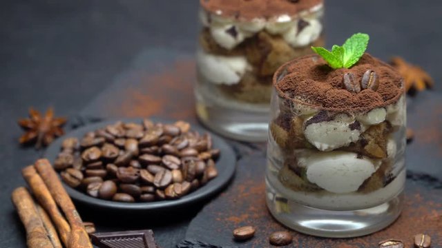 Classic tiramisu dessert in a glass on stone serving board on dark concrete background