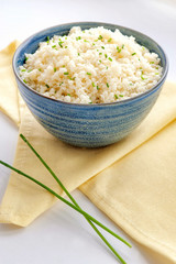 Cauliflower rice. Ketogenic and paleo food. Large portion in a blue bowl on a yellow napkin. Close up and vertical orientation. Copy space.