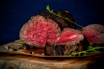 Roast beef from tenderloin A large piece is cut into pieces. A large portion of meat served on a wooden board. Close up and horizontal orientation.
