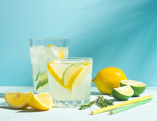 A drink of lemon and lime lemonade in transparent glasses ablue background bright sunlight. Summer...