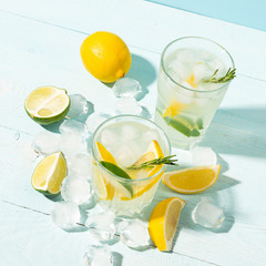 Fototapeta na wymiar A drink of lemon and lime lemonade in transparent glasses a blue background bright sunlight. Summer cocktail or mojito.