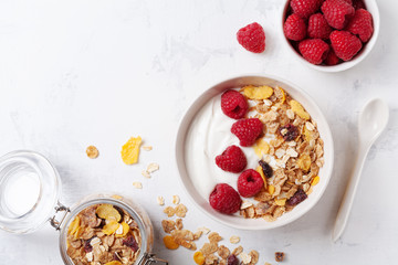 Greek yogurt in bowl with raspberries and muesli on white table top view. Healthy  breakfast. - obrazy, fototapety, plakaty