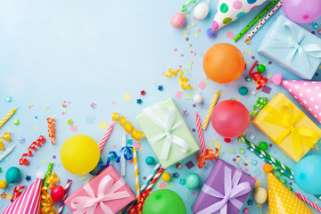 Gift or present boxes, balloons, holiday supplies and confetti on blue table top view. Birthday party greeting card.