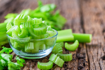 Fresh sliced green celery in glass on wood background,