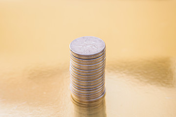 A stack of British coins on a gold background