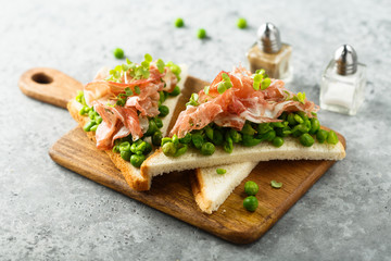 Healthy toasts with pea mash and prosciutto
