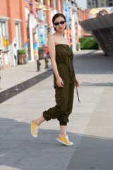Asian Chinese model girl influencer street shot. Wearing army green color jumpsuit. Street Graffiti background.
