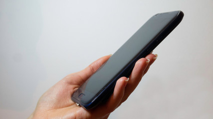 Close up of side view of left female hand holding blank screen phone isolated on white background.