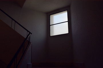 Escaleras interiores eliminadas un poco por la luz de una ventana.