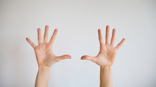 Hands and ten fingers of women raised up in the air on a white background