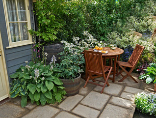 Seating and outdoor eating in a small patio garden with planted containers on the terrace