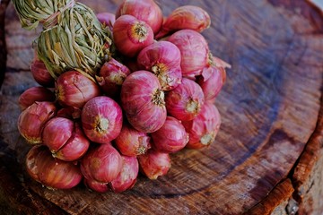 Close up shot of a bundle of red onions on wooden log. Thai ingredient and herb.