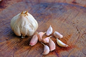 Close up shot of a garlic head and pieces of garlic on wooden log. Thai ingredient and herb.