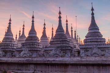 Fototapeta premium White stupas around Sandamuni (Sandamani or Sandar Mu Ni) pagoda during dusk in Mandalay, Myanmar