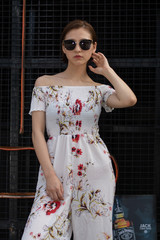 Asian Chinese model girl influencer street shot. Wearing white printed floral patterned jumpsuit.  Street view background.