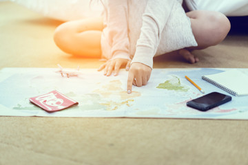 Fototapeta na wymiar Dreaming travel concept .Beautiful young Asian woman with plane, tickets and passport world map beside the bed, pointing to map,The girl who has the desire and ambition to travel around the world.