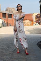 Asian Chinese model girl influencer street shot. Wearing white printed floral patterned jumpsuit.  Street view background.