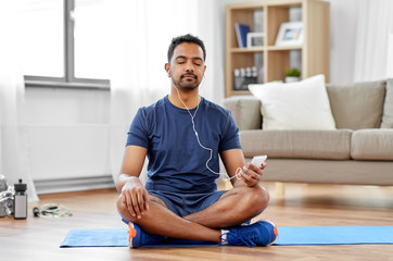 sport, technology and healthy lifestyle concept - indian man in earphones listening to music on...