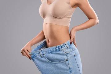 Crop female pulling oversized jeans on slim waist