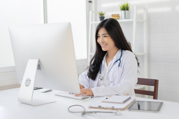 Obraz na płótnie Canvas Asian female doctor work at hospital office desk giving patient convenience online service advice, smiling write a prescription order medical with smartphone, health care, preventing disease concept.