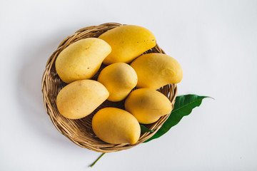 Yellow mango in a basket on a white background