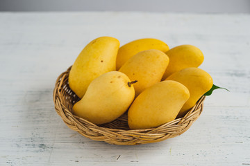 Yellow mango in a basket on a white background